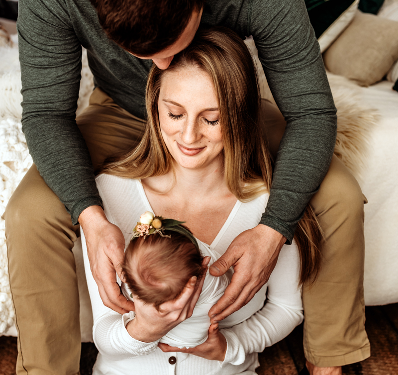 Newborn Photography, mother and father holding child and looking at her sleeping