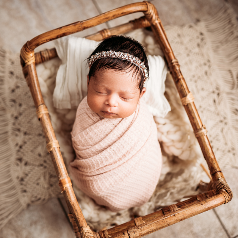 Newborn Photography, sleeping baby in pink swaddle in miniature bed